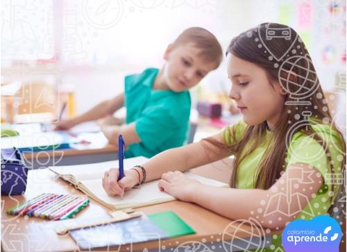 Dos niños sentados en una mesa de escritorio, pintando una cartilla