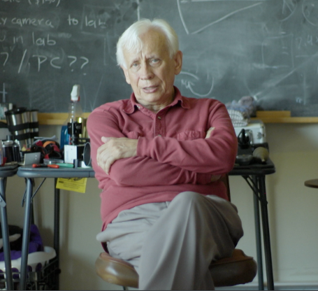 Fotografía de Llinás sentado con los brazos cruzados mirando hacia el frente