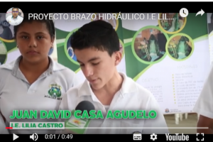 Niño de colegio, vestido con camiseta blanca, con letrero en verde : Juan David Casa Agudelo, proyecto brazo hidráulico