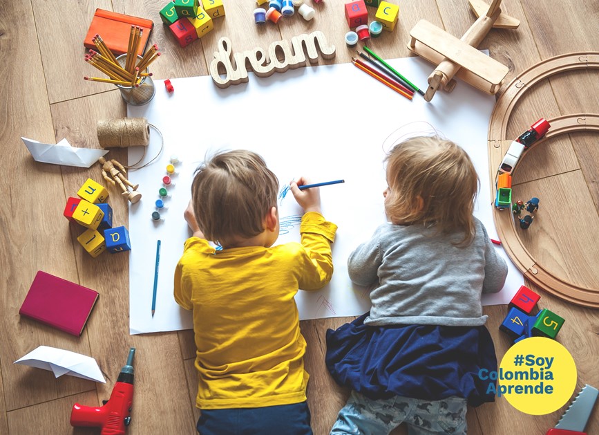 Foto de niño y niña pequeños escribiendo con lápices de colores sobre una cartelera