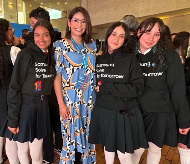 Jefe de Innovación del Ministerio de Educación, Liliana Guaca, posa con tres niñas en uniforme de colegio
