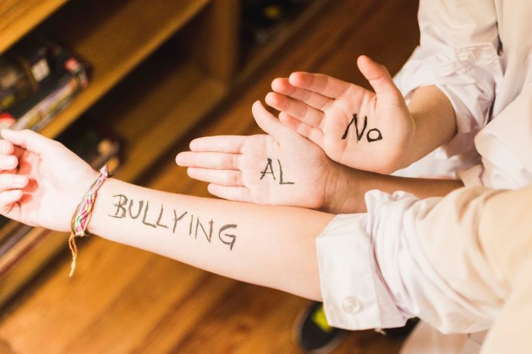 Foto de palmas de manos en las que se lee, No Bullying