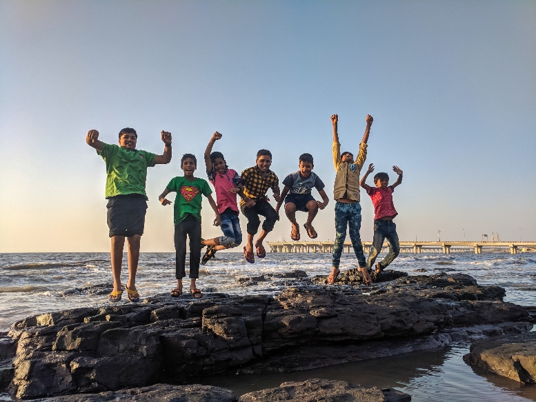 siete niños saltando sobre un tronco a la orilla del mar