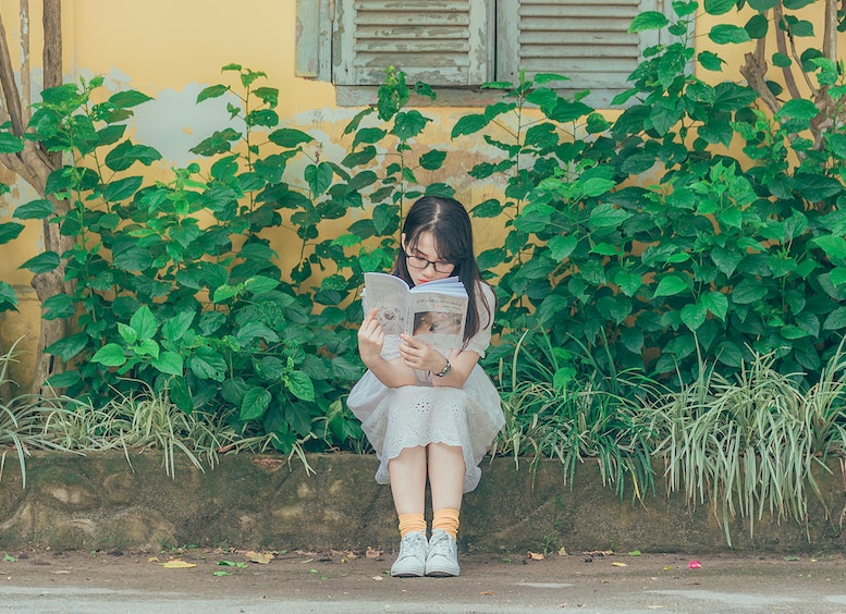 Joven mujer lee libro en un jardin