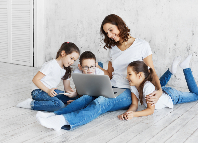 Mamá con tres niños sentados en el piso, mirando un computador portátil
