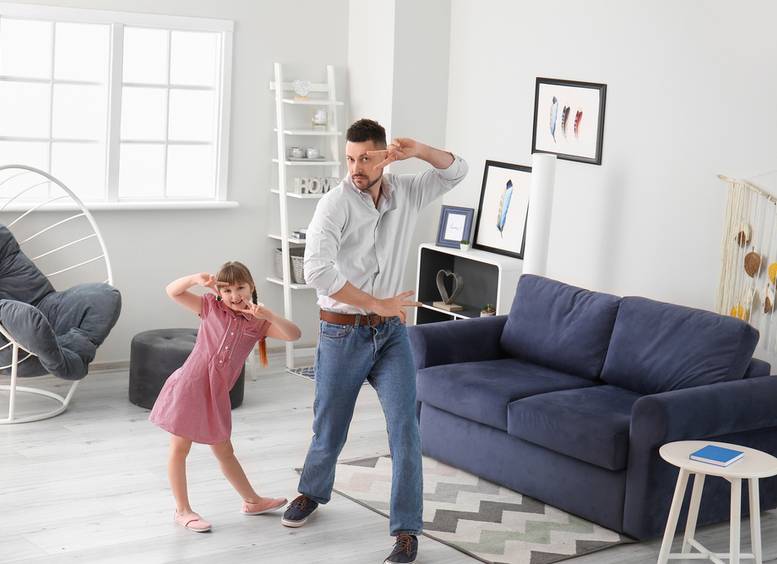 Padre e hija bailando en la sala de la casa