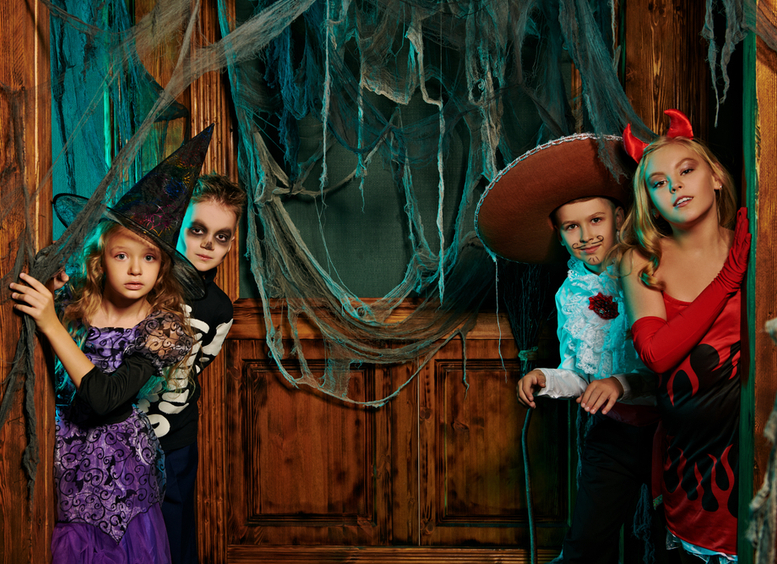 Dos niñas y dos niños disfrazados celebran Halloween en una fiesta con decoraciones de castillos antiguos