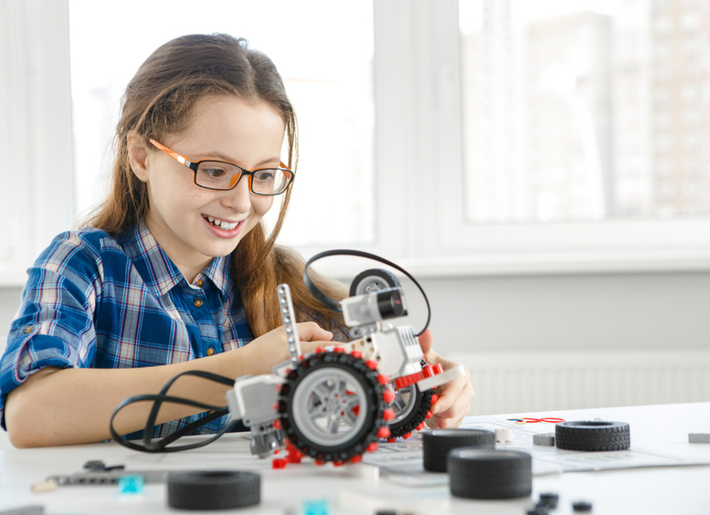 muchacha joven sonriendo y construyendo un robot