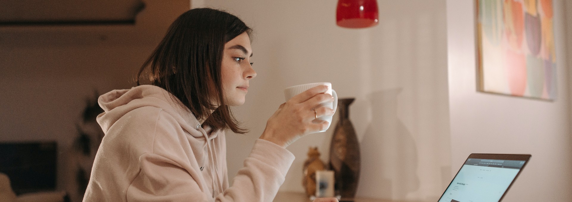 Foto de mujer tomando una taza de café frente al computador