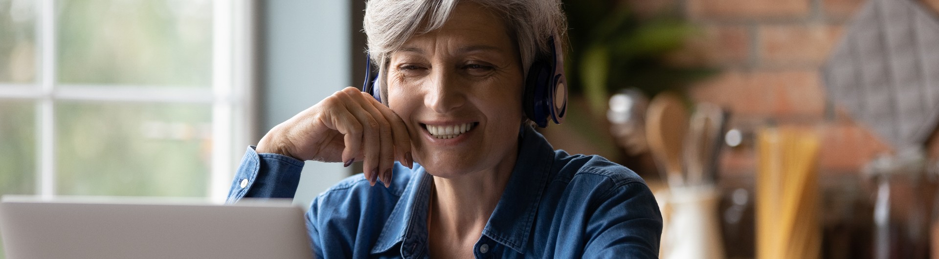 Foto de una señora con audífonos mirando hacia el computador