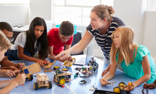 Estudiantes de colegio con profesora, en clase de Codificación De Computadoras Y Aprendizaje Para Programas De Vehículos Robot