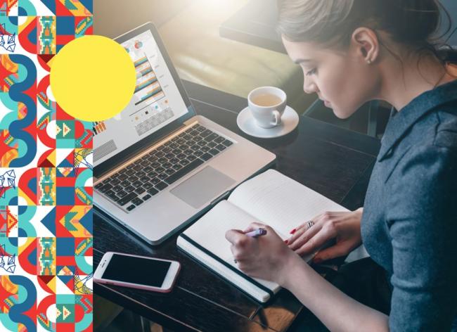 Foto de un joven estudiando en escritorio con cuaderno, computador y café sobre la mesa