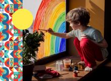 Foto de un niño arrodillado pintando un arco iris