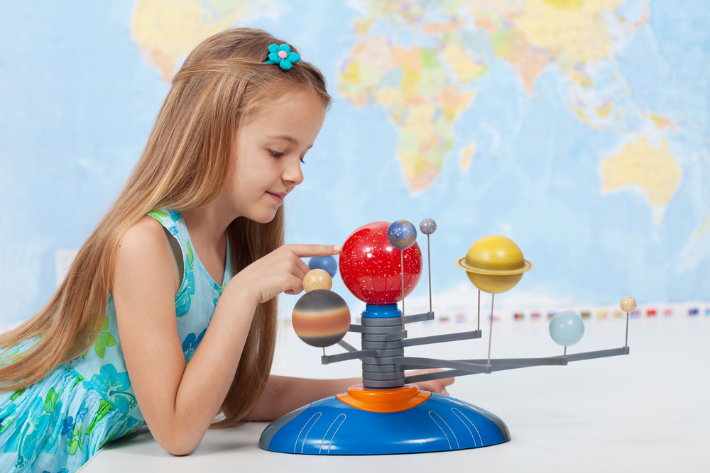 Fotografía de niña explorando maqueta del sistema solar