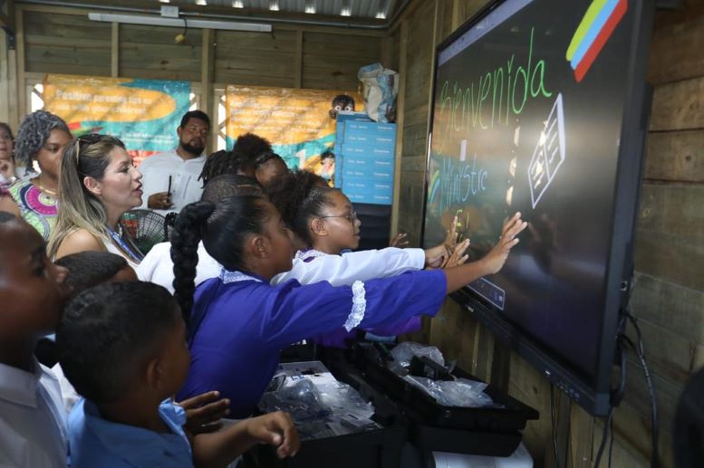 Foto de varios niños de colegio tocando una pantalla interactiva en el aula