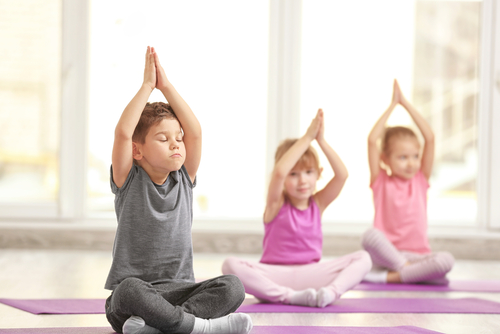 Niños en sesión de yoga y respiración, sentados en el piso