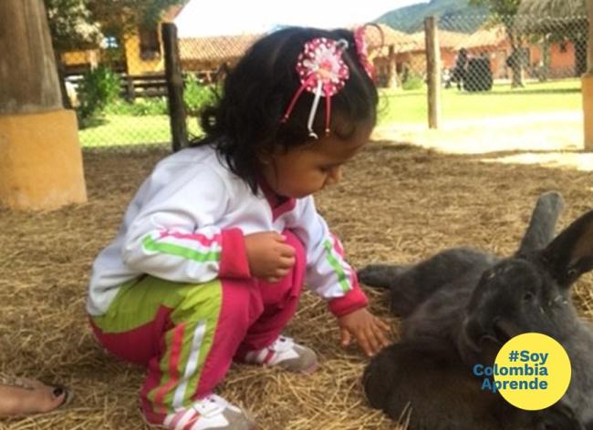 Foto de una niña pequeña jugando con conejo negro